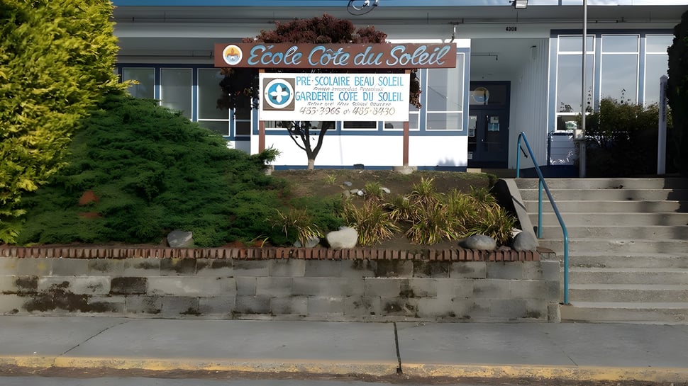 Fachada externa de la École Côte du Soleil con un huerto y plantas en primer plano.