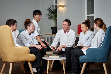 Un grupo de estudiantes de medicina de la École des Sept Sommets realiza una reunión en una sala moderna.