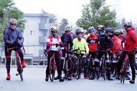Un grupo de estudiantes de la École Entre-Lacs está vestido con colorida ropa de ciclismo frente a un edificio escolar.