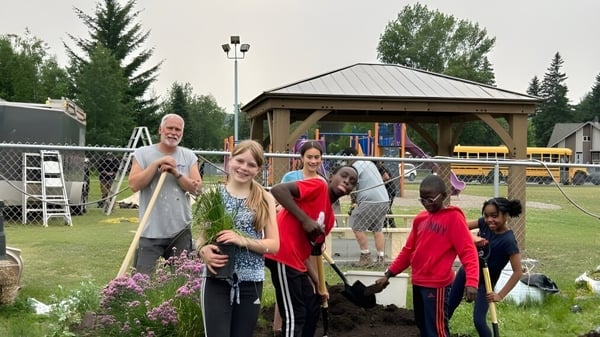 Un grupo de estudiantes y adultos se encuentra en el espacio exterior de la École Franco-Nord con árboles y un pabellón al fondo.