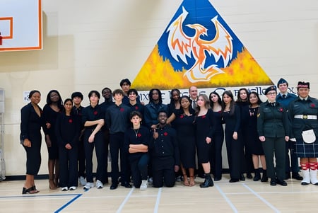 Un grupo de estudiantes está frente a un gran mural con una criatura parecida a un fénix en la École Gabrielle-Roy.
