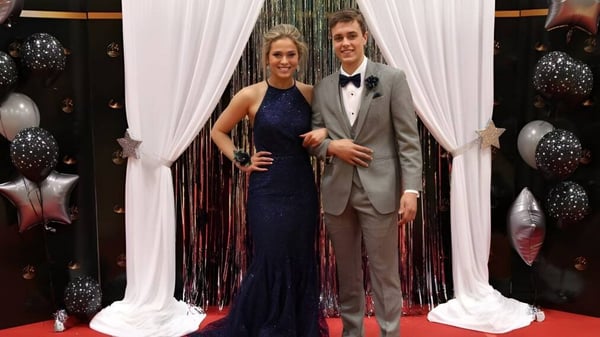 Una joven pareja está frente a un fondo decorativo con cortinas y globos en el campus de la École Marie-Esther.