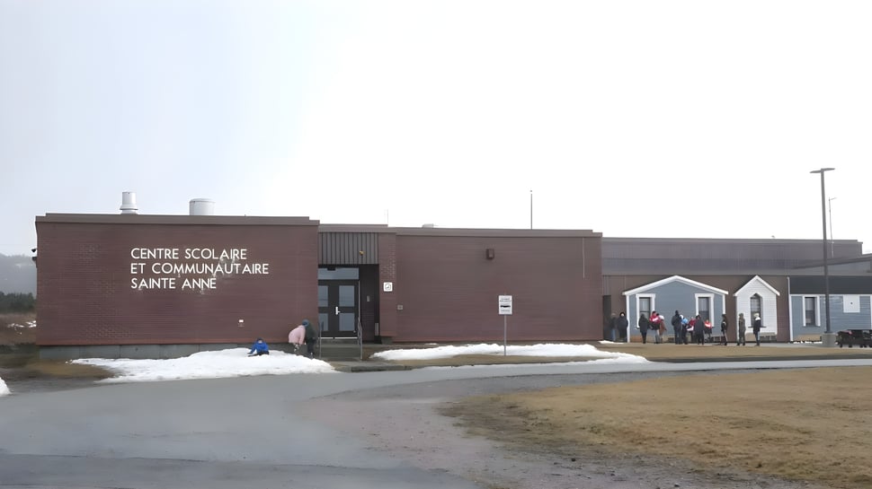 El edificio de la École Sainte-Anne de ladrillos marrones con nieve en el césped circundante.