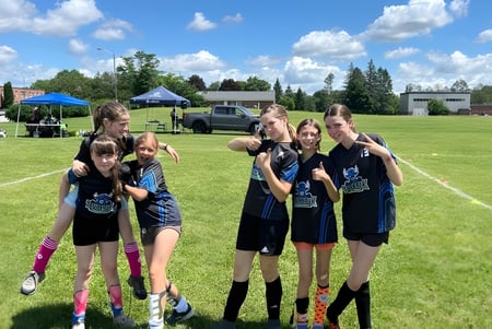 Un grupo de jóvenes atletas está en un campo deportivo en el terreno de la École secondaire publique Rivière Rideau.