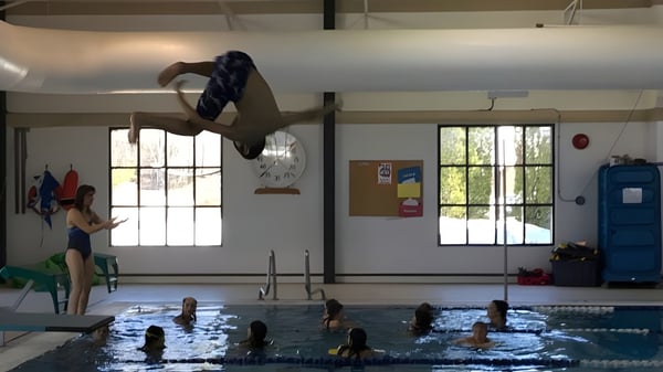 Una persona realiza un salto en la piscina cubierta en el campus de la École Sophie Morigeau.