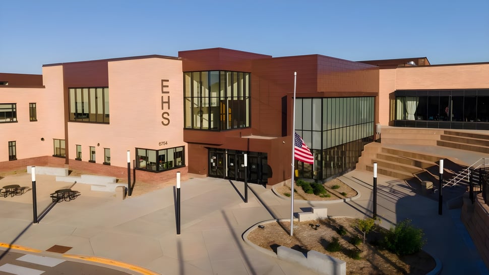 El moderno edificio de ladrillo de Edina Public Schools con grandes ventanas y una bandera americana en primer plano.