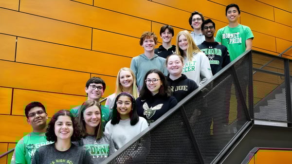Un grupo de estudiantes está en una escalera frente a una pared naranja en el campus de Edina Public Schools.