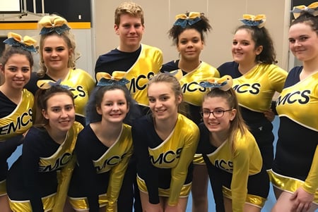 El equipo de cheerleading de la Edward Milne Community School posan juntos en el gimnasio.