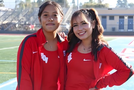 Dos estudiantes de la El Cajon Valley High School están en el campo de deportes frente a un edificio escolar.