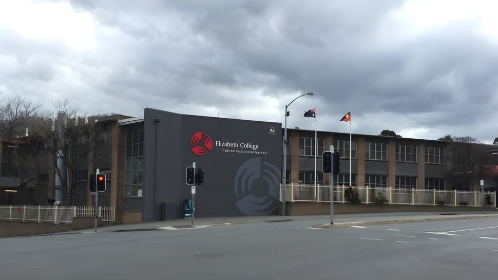 El moderno edificio del Elizabeth College con el logo en la fachada bajo un cielo nublado.