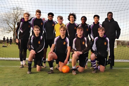 Un grupo de estudiantes del Ellesmere College posa en el campo de fútbol con un balón y la portería de fondo.
