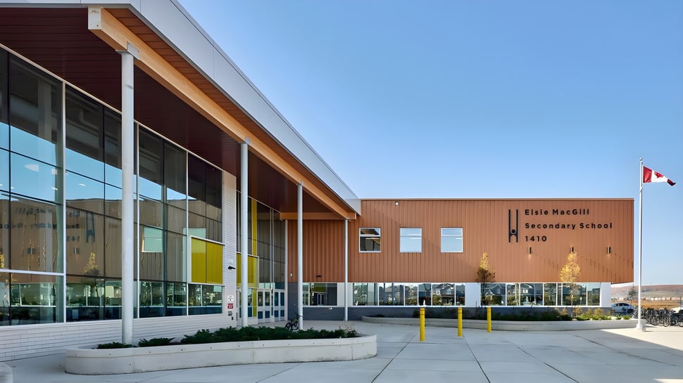 El moderno edificio escolar de la Elsie MacGill Secondary School con grandes ventanales bajo un cielo claro.