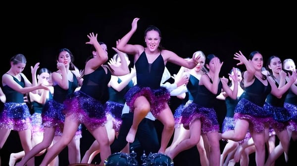 Un grupo de bailarinas presenta una escena en el escenario de la Endeavour Sports High School.