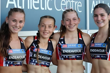 Cuatro alumnas en ropa deportiva están frente al Centro Atlético en el campus de la Endeavour Sports High School.