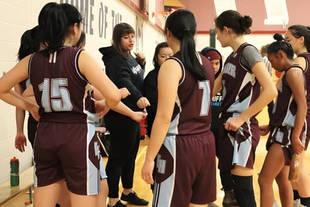 Un grupo de estudiantes de la Eric Hamber Secondary School está en ropa deportiva juntos en un pasillo del edificio escolar.
