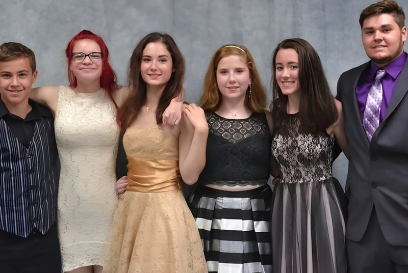 Seis personas en ropa formal posan juntas frente a un fondo gris en una foto de la Erie First Christian Academy.