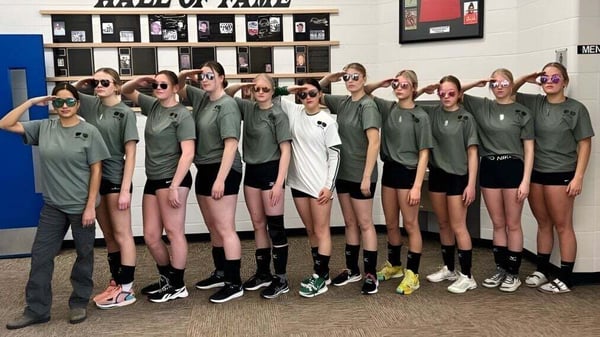 Un grupo de estudiantes de Erle Rivers High School está frente a una pared del Salón de la Fama en el campus escolar.