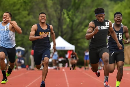 Un grupo de estudiantes de la Ernestown Secondary School corre en la pista con un campo deportivo y árboles de fondo.
