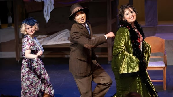 Tres estudiantes de la Escondido Charter High School están en el escenario del teatro con trajes históricos.