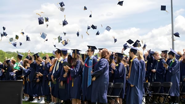 Un grupo de graduados de Essex District High School lanza sus birretes al aire durante la ceremonia de graduación.