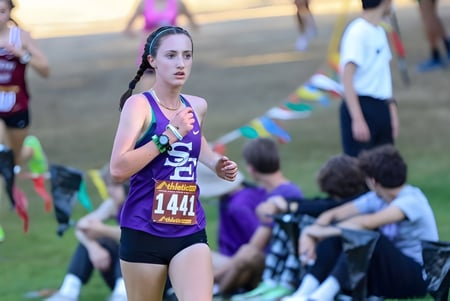 Una corredora con un traje morado participa en una competencia en el terreno del Eugene School District.