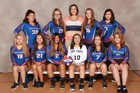 Un grupo de jóvenes jugadoras de voleibol de la Evangel Christian Academy posan en uniformes azules y blancos en el estudio.