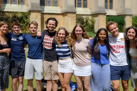 Un grupo de estudiantes está frente a un edificio con arquitectura decorada en el campus del Exeter College.