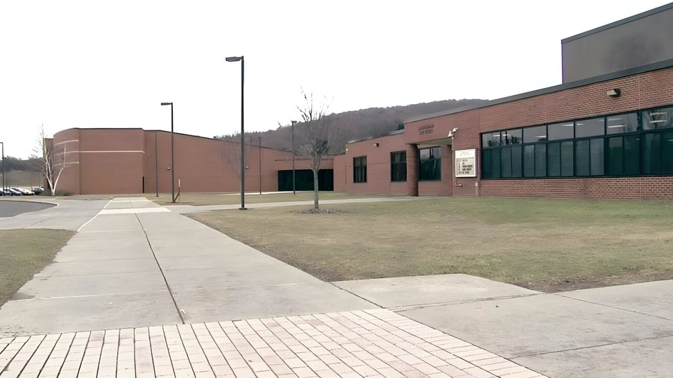 El edificio de ladrillo con grandes ventanas y el camino circundante de la Fabius Pompey High School.