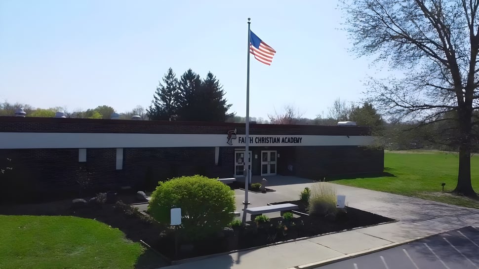 El edificio principal de la Faith Christian Academy (PA) con una bandera americana en el cuidado exterior.
