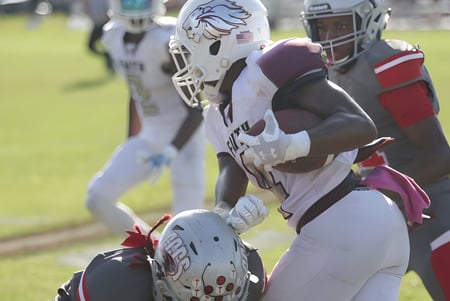 Dos jugadores de fútbol americano de la Faith Christian Academy (FL) están activos en un juego en el campo.