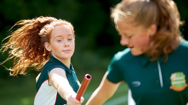 Dos alumnas de la Farringtons School mantienen una conversación al aire libre frente a un fondo verde.
