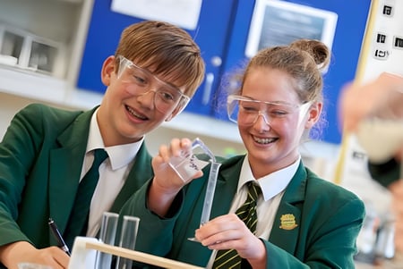Dos alumnas de la Farringtons School conversan riendo en el aula con paredes azules.