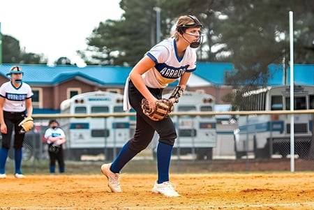 Una estudiante de la Fayetteville Christian School está en el campo de béisbol con el diamante de béisbol y edificios al fondo.