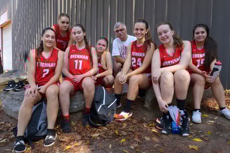 Un grupo de estudiantes de la FJ Brennan Catholic High School está sentado en el suelo rodeado de hojas de otoño.