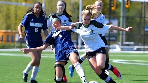 Estudiantes de la Fleetwood Park Secondary School juegan al fútbol y luchan por el balón en el campo.