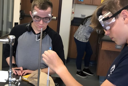 Dos estudiantes de la Fleetwood Park Secondary School examinan un dispositivo en el laboratorio de taller.