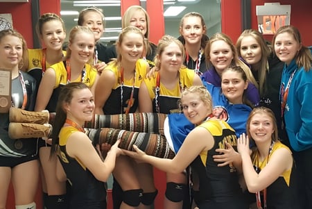 Un grupo de jóvenes estudiantes de la Forestburg School se reúne sonriendo en un gimnasio.