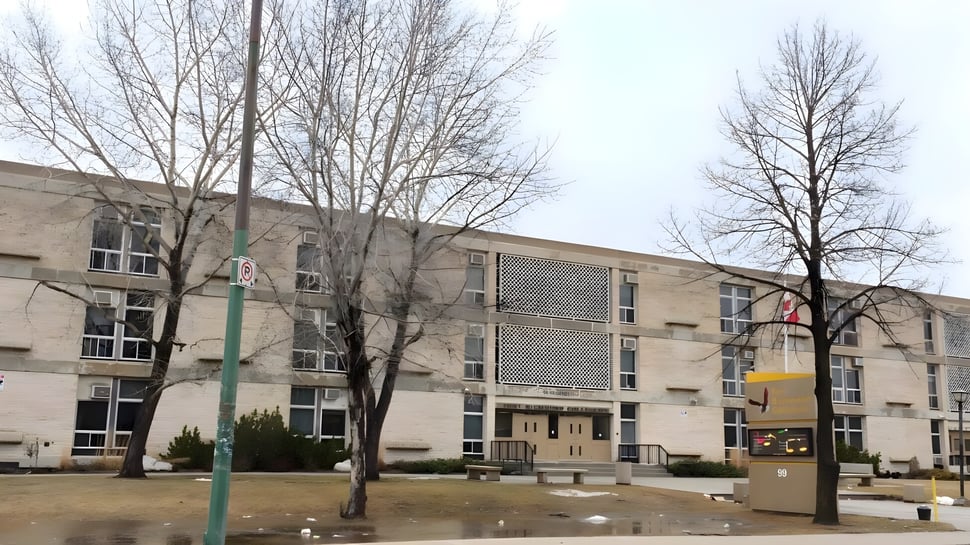 El edificio de ladrillo de varios pisos con árboles desnudos y una superficie de césped muestra el Fort Richmond Collegiate.