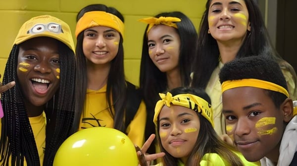 Un grupo de estudiantes con accesorios amarillos posan juntos en el campus del Fort Richmond Collegiate.