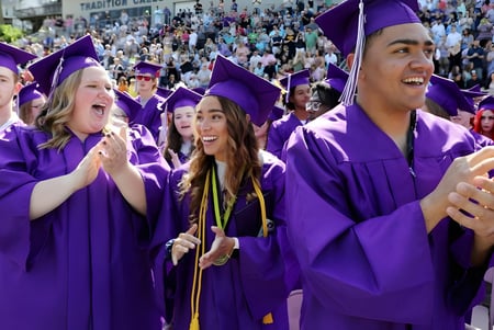 Las graduadas y graduados de la Fort St. James Secondary celebran al aire libre su graduación en togas moradas.