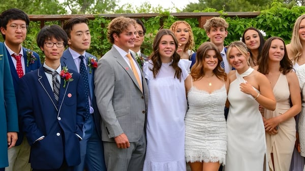 Un grupo de estudiantes de la Fountain Valley School of Colorado está junto en el área verde exterior frente a una estructura de madera.