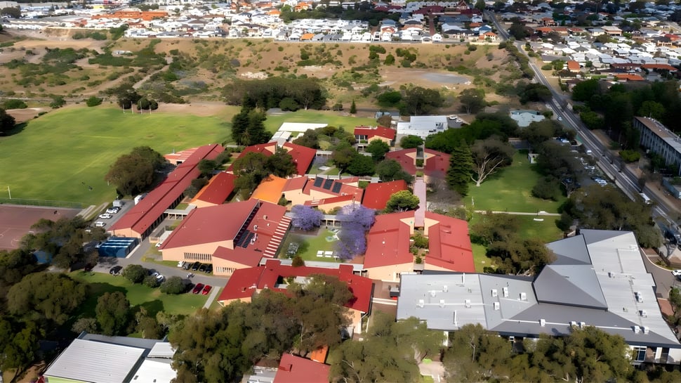 Un área residencial con techos rojos y mucho verde en el entorno montañoso cerca del Fremantle College.