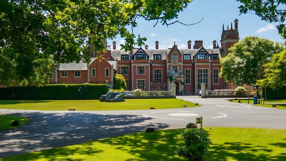 El venerable edificio de la Frensham Heights School está incrustado en un jardín cuidado con árboles y un tranquilo estanque delante.