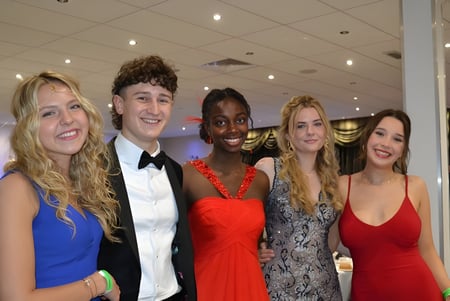 Un grupo de cinco jóvenes adultos en ropa formal en una fiesta en el campus de la Frensham Heights School.