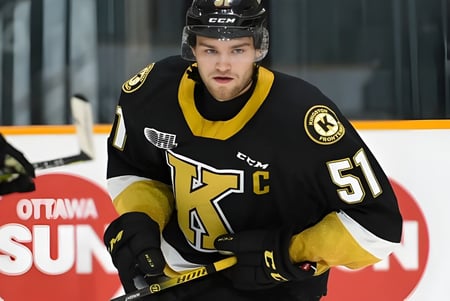 Un jugador de hockey con uniforme negro y amarillo sobre el hielo de la Frontenac Secondary School.