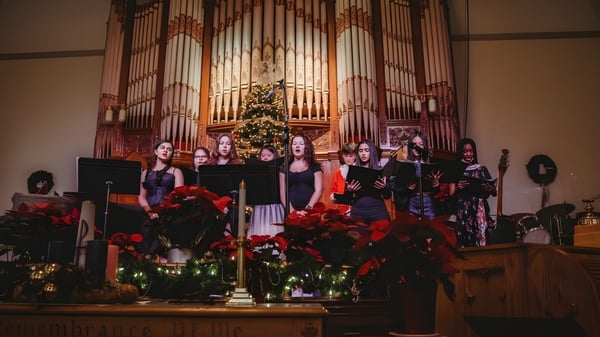 Un grupo de coro de la Fulford Academy canta en un escenario frente a un gran órgano en una iglesia decorada festivamente.
