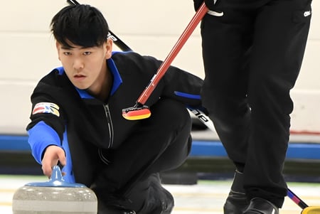 Una estudiante de la Fulford Academy sostiene una piedra de curling en la pista de hielo durante la clase de educación física.