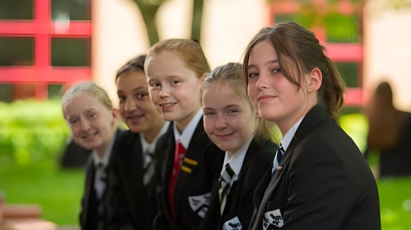 Un grupo de estudiantes en uniformes escolares está junto afuera en el terreno de la Fulston Manor.