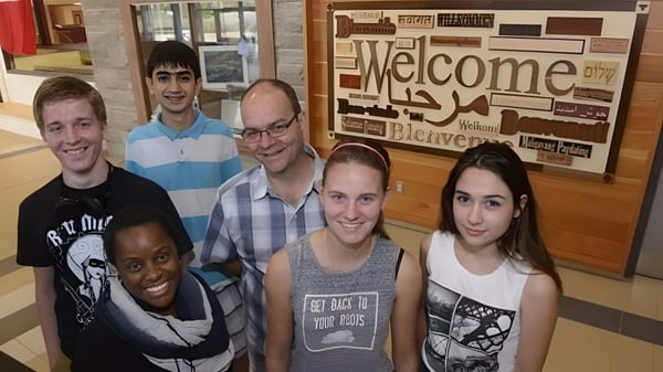 Un grupo de estudiantes está frente a un cartel de bienvenida en el campus de la Garth Webb Secondary School.