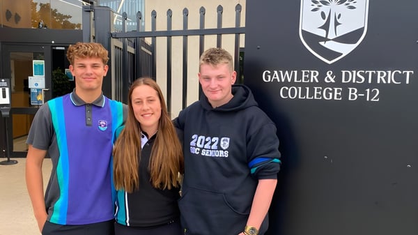 Tres estudiantes están frente al cartel del Gawler and District College.